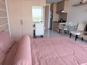 a bedroom with a pink bed and a kitchen at Whale Marina Condo in Na Jomtien +32 photos