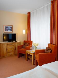 a hotel room with two chairs and a television at Hotel Gutenberg in Westerland +14 photos
