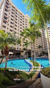 a hotel with a pool and palm trees in front of it at Boulevard suite hotel apartamento 434 in Caldas Novas