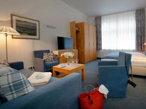 a hotel room with a blue couch and chairs and a bed at Hotel Gutenberg in Westerland