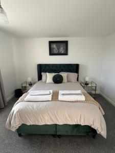a bedroom with a large green bed with two tables at Silver stays, calm coastal stay , close to beach in Gorleston-on-Sea +25 photos