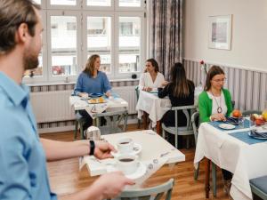 a group of people sitting at tables in a restaurant at Hotel Gutenberg in Westerland