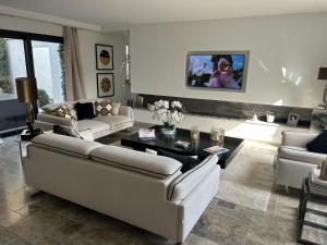 a living room with couches and a tv on the wall at Superbe villa golfe st Tropez in Sainte-Maxime