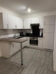 a kitchen with white cabinets and a table in it at Lingen Stay in Lingen