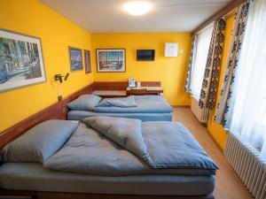 three beds in a room with yellow walls at Gasthof zum Falken in Frauenfeld