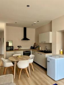 a kitchen with a table and some chairs and a table and a counter at Appartement Saint-Louis in Verdun-sur-Meuse