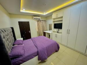 a bedroom with a purple bed and a television at Abuja Circa Suite in Abuja