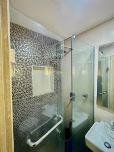 a bathroom with a glass shower and a sink at Abuja Circa Suite in Abuja