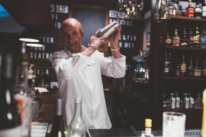 a man standing behind a bar holding a bottle at Fliegerdeich Hotel & Restaurant in Wilhelmshaven
