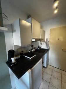 a kitchen with a black counter top and white cabinets at 1-Zimmer Apartment Waldperle in Erftstadt