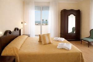 a bedroom with a bed with two towels on it at Hotel Milano Helvetia - in centro con piscina in Riccione