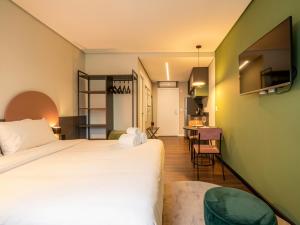 a hotel room with a bed and a dining room at Xtay Cais Rooftop -Estúdios completos e Rooftop para o Rio Guaíba in Porto Alegre