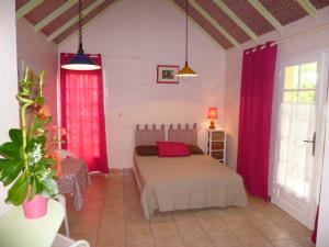 a bedroom with a bed and red drapes at Antilles Liberte in Sainte-Anne
