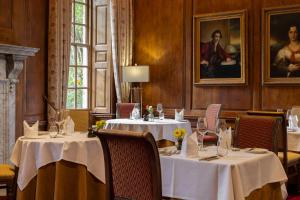 a dining room with two tables with white table cloth at Hintlesham Hall Hotel in Ipswich +57 photos
