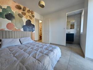 a bedroom with a large bed and a bathroom at Gîte Le Granit des Champs in Mainsat