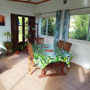 a dining room with a table and chairs and windows at Le Tranquillou in La Plaine des Cafres