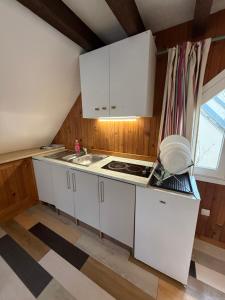 a kitchen with white cabinets and a sink and a window at LK gîte la forêt in Chénérailles