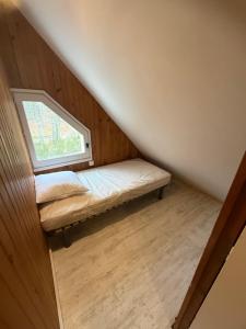 a small bed in a room with a window at LK gîte la forêt in Chénérailles