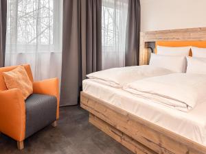 a bedroom with a bed and a chair at THE GOOD ONE Hotel Landshut in Landshut