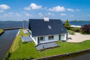 a small house on a small island in the water at Villa Verderop - Luxury Lakeside Villa with Terrace & Water Views in Friesland in Boornzwaag