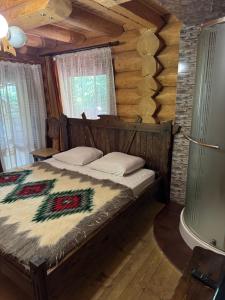 a bedroom with a bed in a log cabin at Бистриця in Chynadiyovo