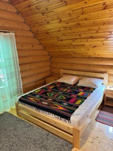 a bed in a room with a wooden wall at Бистриця in Chynadiyovo +7 photos