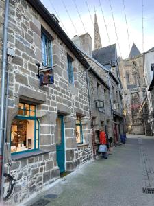 an old stone building with blue doors on a street at Centre Treguier L escapade des quais in Tréguier