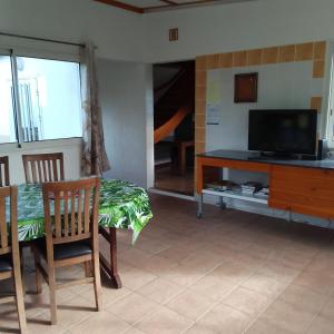 a living room with a table and a television at Le Tranquillou in La Plaine des Cafres
