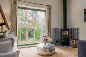 a living room with a fireplace and a large window at The Old Workshop, Combrook in Combrook