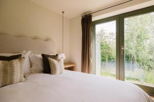 a bedroom with a white bed with a large window at The Old Workshop, Combrook in Combrook