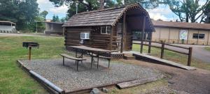 a small log cabin with a picnic table and a bench at Texarkana KOA Journey in Texarkana