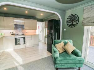 a living room with a green chair and a kitchen at The Nest Lodge 55 in Grantham