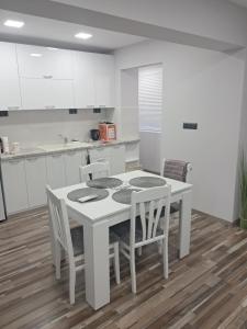 a white kitchen with a white table and chairs at Apartment Petrovi in Lovech +12 photos