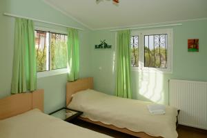 a bedroom with two beds and green curtains at Athenian Spiti in Artemida