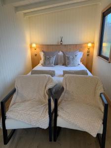 a bedroom with two beds and two chairs at Luxury Shepherds Hut with Hot Tub Valley Views in Scarborough