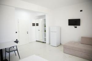 a white living room with a couch and a tv at Vila Lori in Ksamil