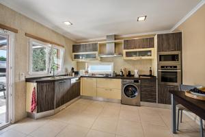 a kitchen with wooden cabinets and a washer and dryer at Casa Jacadi Luxury Villa, Private Pool, Rooftop terrace with sea View! in Armação de Pêra