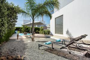 a patio with a chaise lounge and a palm tree at Casa Jacadi Luxury Villa, Private Pool, Rooftop terrace with sea View! in Armação de Pêra