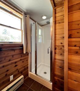 a walk in shower in a bathroom with wooden walls at Seabreeze #3 - Cozy cottage by the beach in Hampton Bays