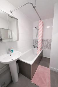 a white bathroom with a sink and a bath tub at Sutton Cosy Rooms in Sutton