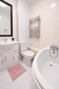 a white bathroom with a toilet and a tub and a sink at Sutton Cosy Rooms in Sutton