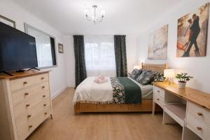 a bedroom with a bed and a desk with a television at Sutton Cosy Rooms in Sutton