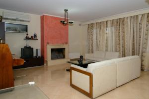 a living room with a white couch and a fireplace at Athenian Spiti in Artemida