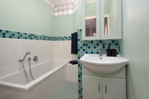 a white bathroom with a sink and a bath tub at Fynbosrus on Grotto in Hermanus +24 photos
