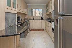 a large kitchen with white cabinets and granite counter tops at Fynbosrus on Grotto in Hermanus
