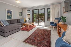 a living room with a couch and a table at Fynbosrus on Grotto in Hermanus