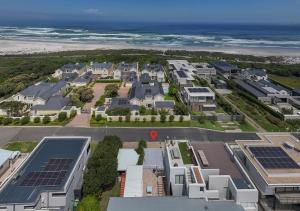 an aerial view of houses with solar panels and the ocean at Fynbosrus on Grotto in Hermanus