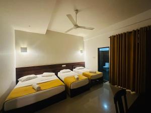 a bedroom with three beds and a ceiling fan at Hotel Divine Light Monaragala in Monaragala