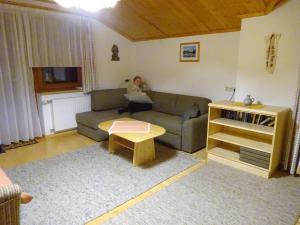 a woman sitting on a couch in a living room at Ferienwohnung Mützengruß in Filzmoos