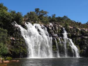 a waterfall in the middle of a body of water at Chalé Chapada dos Veadeiros in Cavalcante +20 photos
